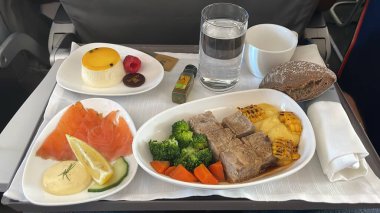 Alicante, İspanya - 4 Ekim 2023. Alicante 'den kalkmak üzere olan bir İberya uçağındaki yemek tepsisi. Somon salatası domuz tatlısı. Normal sınıfa kıyasla birinci sınıfın önemli avantajları