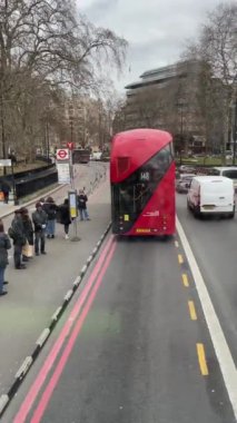 Londra, İngiltere - 3 Mart 2023. 148 numaralı Modern Red otobüsü Westminster bölgesinde bir otobüs durağından ayrılıyor. Şehirdeki trafik yüzünden. Yüksek kalite 4k dikey görüntü