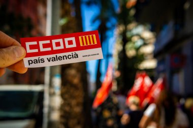 Alicante, Spain - September 26th 2024. CCOO Pais Valencia trade union logo in the foreground. In the background a demonstration for labour rights clipart