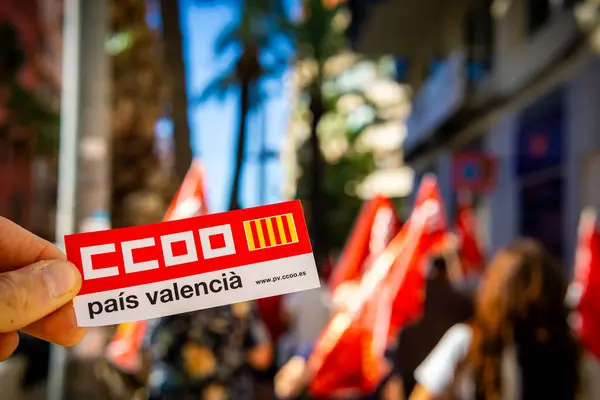 Alicante, İspanya - 26 Eylül 2024. CCOO Pais Valencia Ticaret Sendikası logosu ön planda. Arka planda çalışma hakları için bir gösteri