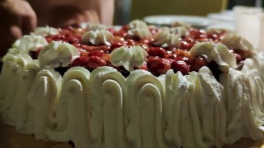 Bir wuman, beyaz kremalı keki yakın plan bıçakla keser. Doğum günü pastasına kırmızı çilek serpin. Pastadaki krema tatlısı. Çocuklar Pastadan Bir Parça Bekliyor. Yakın plan. 4K UHD