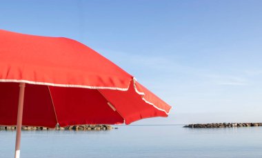 Sahildeki Kırmızı Şemsiye. Plaj Şemsiyesi, Yaz Arkaplanı. Tatil ve Aile Tatili. Vücutta Yanıklara Karşı Koruma Şemsiyesi.