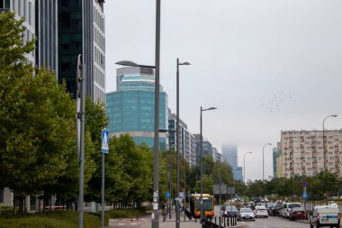 30 Ağustos 2022: Varşova 'da Arabalar, Otobüsler. Polonya. İnsanlar kırmızı ışıkta durur, yayalar caddeyi geçer. Arka planda tramvaylar, metro girişleri, binalar var..