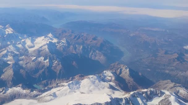 空から山の完璧なショット 曲がりくねった道や湖と青空の下で雪の山の範囲の空中ビュー — ストック動画
