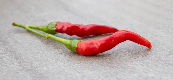 Red hot chili pepper on a gray background. Red fresh chili pepper, seasoning for dish, hot pepper, hot spices for cooking, cayenne pepper, food.