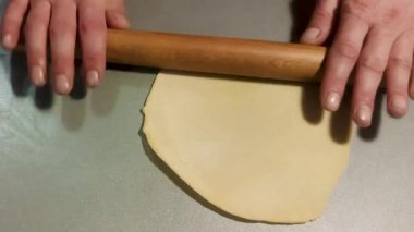 A Man Rolls out Dough on the Kitchen Table. Male Hands Roll Out the Dough With a Rolling Pin, Close-up. A Man Prepares Food at Home. 4k in Real Time.