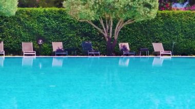 Swimming Pool and Terrace in a Tropical Resort. Sun Loungers on the Terraces by the pool in an Exotic Hotel. Wide Outdoor Swimming Pool with Palm Trees in the Background.