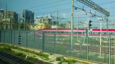 A Modern Red Train Against a Blue Sky and Skyscrapers on a Warm Summer Day in Italy. Fly to the Train. Amazing Cinematic Shot.