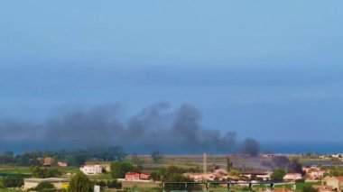 A Wide Shot of Smoke Coming Out of a Burning House. A Pillar of Smoke From a Fire in a City on the Coast of the Tyrrhenian Sea in Calabria, South of Italy. Aerial View.