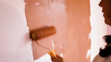 A Woman Paints a Wall in Her Apartment. Joyful Female Artist Works in a New Apartment During House Renovation.