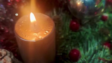 Burning Candle. Thick Yellow Christmas Candle on a Green Background. The Flame of the Candle Burns and Dances.
