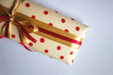 Flat Fantastic Wrapped Gift Decorated With a Bow on a Light Background. Top View of Gift Wrapping with Red and Yellow Ribbon with Copy Space.