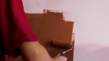The Guy Paints the Wall With Brown Paint Using a Roller. Builder, Tool, Apartment Renovation.