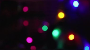 Farklı renklerin parıltıları. Tasarım. Parlayan Ampuller Hareketlerle Soyutlanarak Yapılır. Odaklanmamış Çok Renkli Çemberler Siyah Arkaplanda Hareket Ediyor.