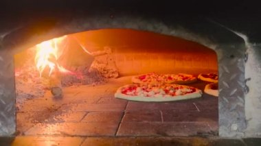 Pizza pişiriyorum. Şef, restoranın mutfağında pizza hazırlıyor. Büyük Hamur 'lu İtalyan Napoli Pizzası. Mutfakta çalış. Pizza, odun ateşinde bir fırına konur. Modern fırın. Pizza..