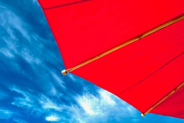 Sahildeki Red Beach Şemsiyesi. Mavi Gökyüzü Arkaplanında Bulutlu Şemsiye.