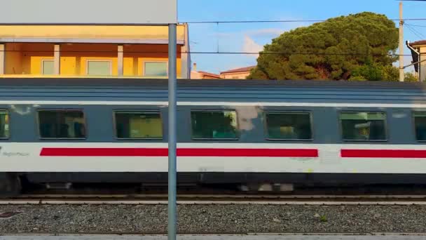 カラブリア州を旅する赤いストライプの白い旅客列車 イタリアで停止せずに駅を通過する旅客ディーゼル列車 — ストック動画