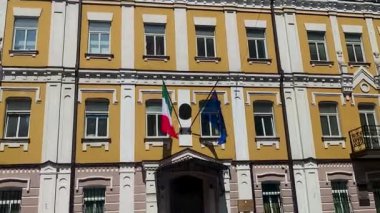 Elçilik binasının ön cephesinde İtalya ve Avrupa Birliği bayrağı var. Ukrayna, Kyiv 'de bir binaya karşı rüzgarda dalgalanan renkli pankartlar.