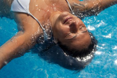 Zhytomyr, Ukrayna, 18 Ağustos 2023: Yüzme havuzunda dinlenen mutlu kadın. Kıdemli kadın yaz tatilinin tadını çıkarıyor..