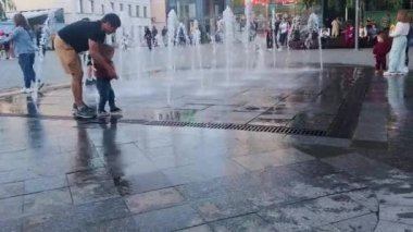 Kyiv, Ukrayna, 14 Ekim 2023: Baba ve oğul Ukrayna çeşmesinin yanında oynuyorlar. Bir baba oğluyla fıskiyenin fıskiyesinde oynar. Çocuklu aileler için yaz tatili.