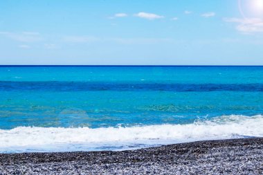 Parlayan Su. Sakin deniz ya da okyanus yüzeyinde küçük dalgalar ve mavi gökyüzü.