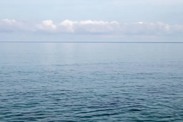 Mavi okyanus manzarası, berrak gökyüzü, dalgalı dalga ve güzel güneş ışığıyla sakin deniz manzarası..