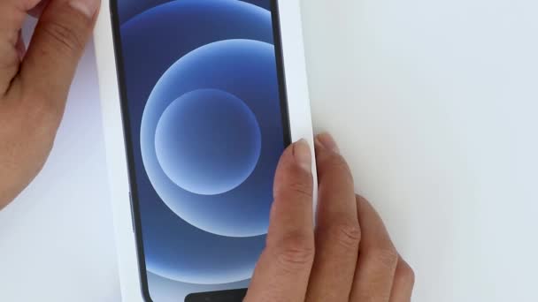 德国慕尼黑 2024年4月2日 女性的手打开一个新的苹果从盒子 最新的Iphone 13特写 用白色背景的新智能手机打开盒子的手 — 图库视频影像