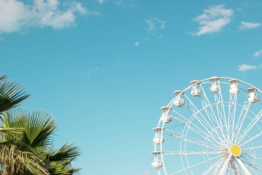 Mavi gökyüzüne karşı beyaz dönme dolap. Mutlu bir yaz tatili hissi.