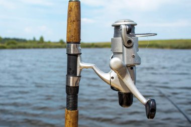 Gölün arka planında bir olta ve makara. Rahatlamak için balık tutma zamanı..