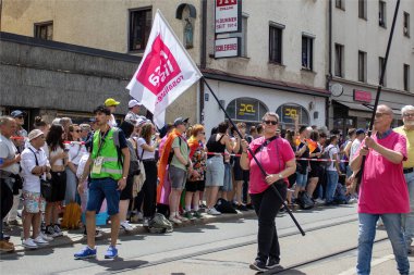 Münih, Almanya, 22 Haziran 2024: Almanya 'da Onur Festivali Geçidi. Eşitliği destekleyen bir gösteride bayrak ve afişlerle kutlama. İnsanlar birlikte eğleniyor..