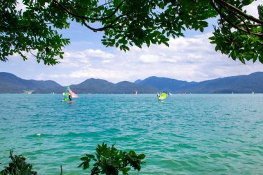 Kochel, Almanya, 27 Temmuz 2024: Bavyera 'da Walchensee' de rüzgar sörfü. Güneşli hava ve güzel Alpler manzarası..