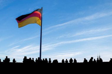 Alman bayrağı, ulusal bayram dekorasyonu için siluetli kalabalığın arasında yer alıyor.