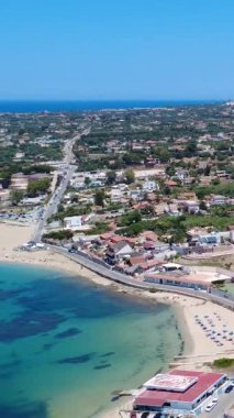 Güneşli bir günde berrak mavi suyu ve gür yeşilliği olan canlı bir sahil kasabasının güzel kıyı manzarası