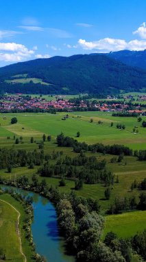 Bereketli yeşil tarlalar, berrak mavi bir gökyüzünün altında kıvrımlı bir nehre doğru uzanır. Görkemli dağların arka planına yakın, tuhaf köyler yuva yapar..