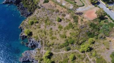 Parlak Güneş Işığındaki Sahil Manzarası Kayalar ve Yeşilliklerle Huzurlu Mavi Deniz