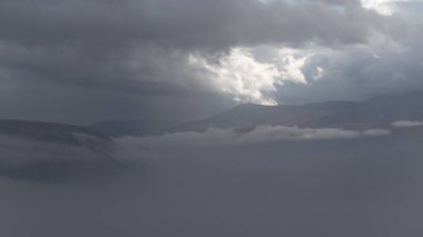 Dramatic landscape with mountain peak between fog and clouds, autumn season in mountains