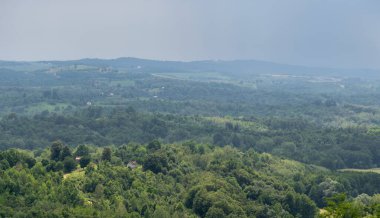 Yazın çoklu hava koşullarıyla kırsal alan, bereketli ormanlarla çevrili kırsal çiftlik evindeki güneş lekesi ve arka planda bulutlarla kaplı kasvetli bir köy.