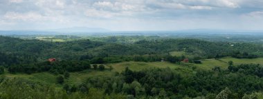 Dağlık kırsal manzara ve sisli vadi, yazın bereketli ormanları olan panoramik köy manzarası ve güneşli bir günde bulutlarla dolu vadi.