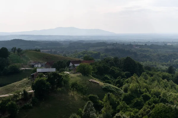 stock image Farmhouse on hill and mountain silhouette in distance, air haze