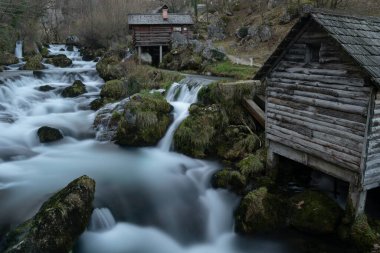 Yosun kayaları ve ahşap su değirmenleriyle dolu dağ nehri, Krupa na Vrbasu nehri.