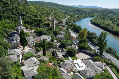 Güneşli bir günde Neretva nehrinin kıyısında cami ve saat kulesi olan Ortaçağ kasabası Pocitelj