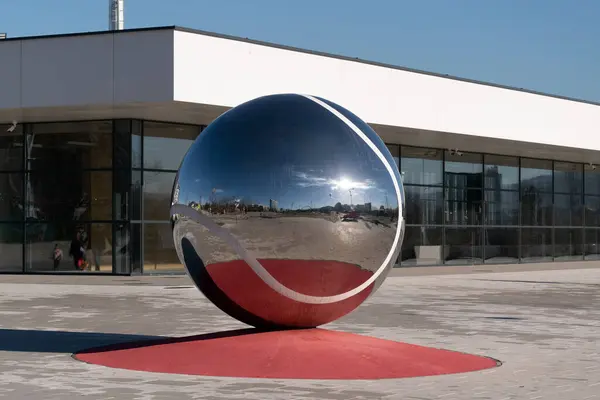 Tenis kompleksinin önündeki büyük tenis topu, parlak ve yansıtıcı.