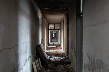 Terk edilmiş ofis binasındaki dağınık koridorda kundaklama izleri ve duvarlar var.