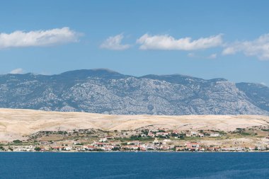 Pag island with coastal settlement and mountain Velebit in haze clipart