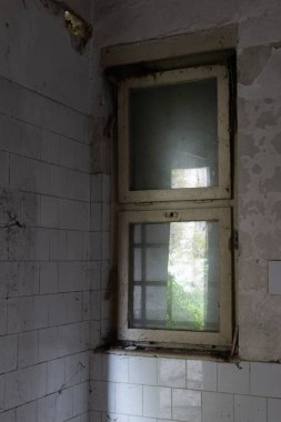 Duvarları ve pencereleri olan boş bir odanın köşesi, cama yansıyan ışık.