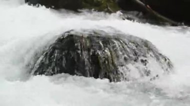 Vahşi dağ deresindeki büyük kayaların üzerinden su akıntısı.