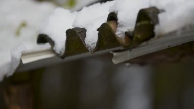 Çatıda eriyen karlar, yakın mesafeden süzülen su kıvrımlı asbest çatılardan damlıyor.