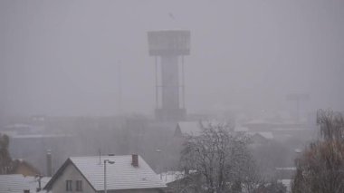 Kar yağışı sırasında su kulesi, şehir manzarası