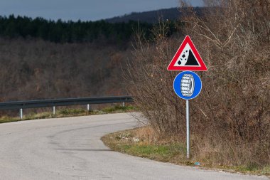 Dağlardaki asfalt yolun yanındaki kayalık ve kar zincirleri için yol işaretleri