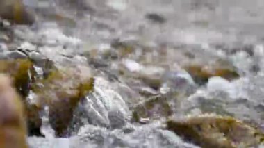 Dağ deresindeki taşların üzerinden akan sular, temiz suyla birlikte dereden gelen detaylar.